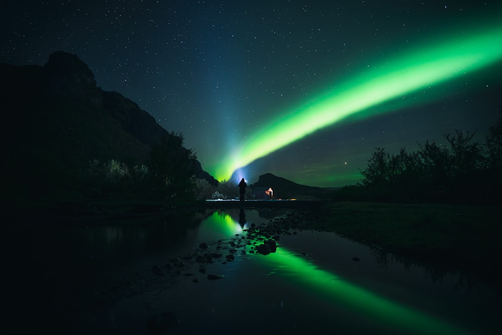 a body of water with a bright green light in the sky above