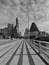 a road with a railing and buildings on the side