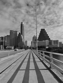 a road with a railing and buildings on the side