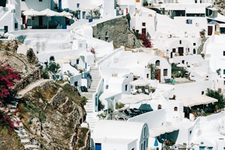 A charming whitewashed village on a Greek island with vibrant bougainvillea climbing the walls under a bright blue sky.