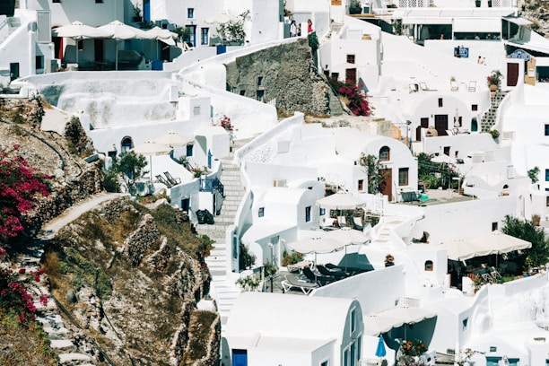 A charming whitewashed village on a Greek island with vibrant bougainvillea climbing the walls under a bright blue sky.