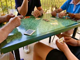 A family gathered around a table playing a printed card game.