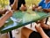 A group of friends gathered around a table, playing a trivia card game together.