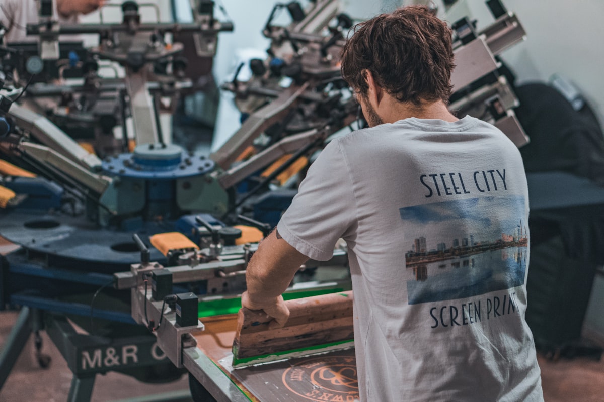 Worker in a custom apparel print shop preparing a production run
