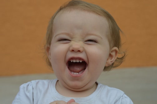 A candid shot of a child laughing, eyes sparkling with pure joy against a minimalist background.