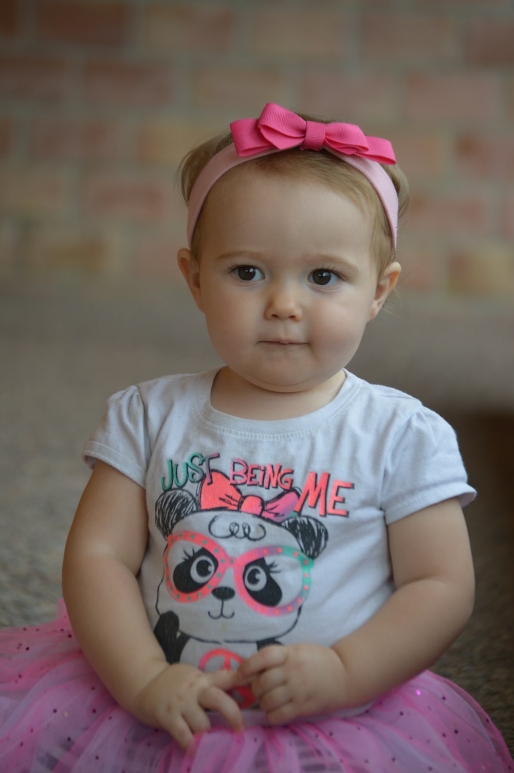 a baby girl sitting on the ground