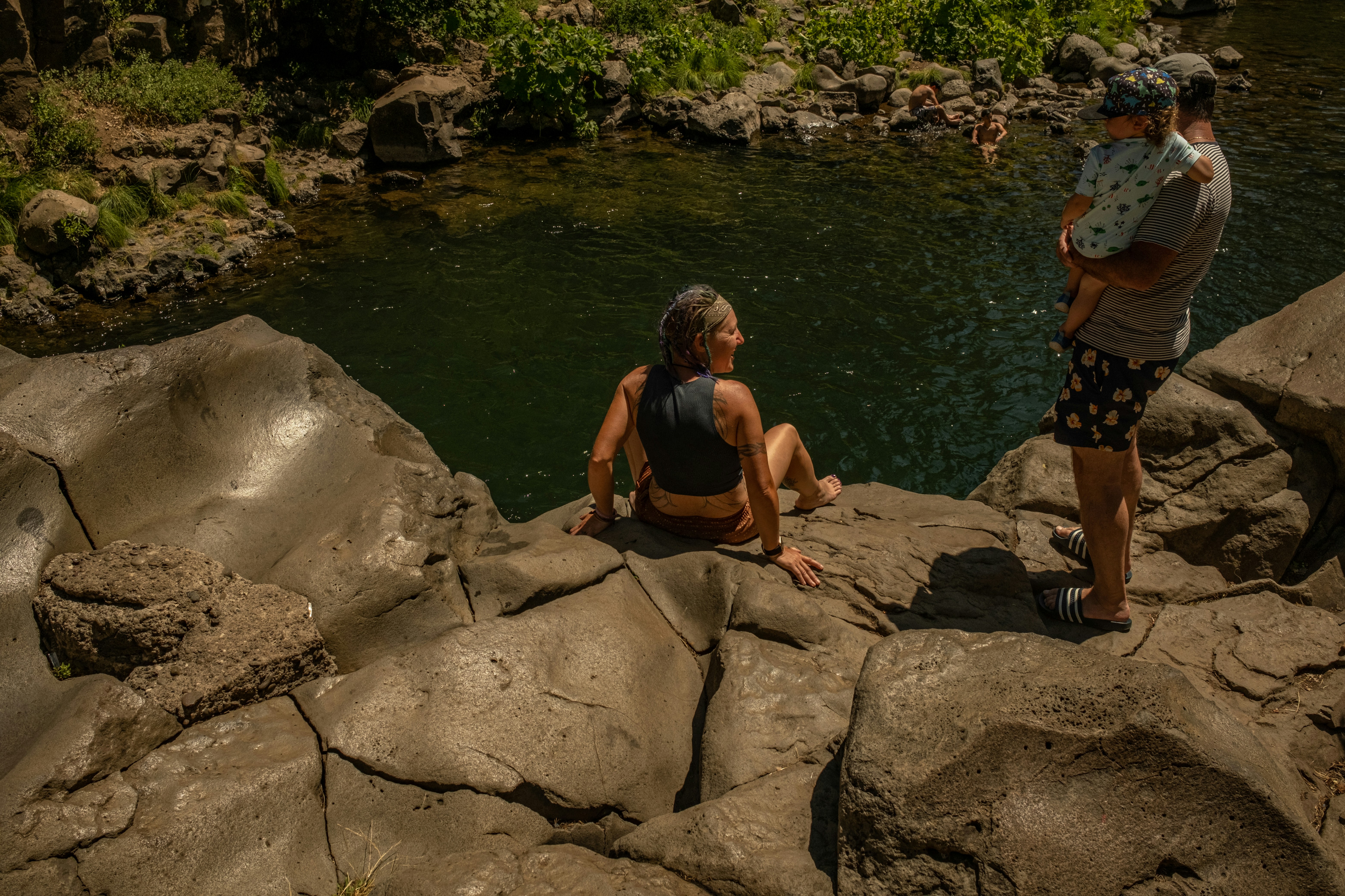 A man sitting on rocks by a river