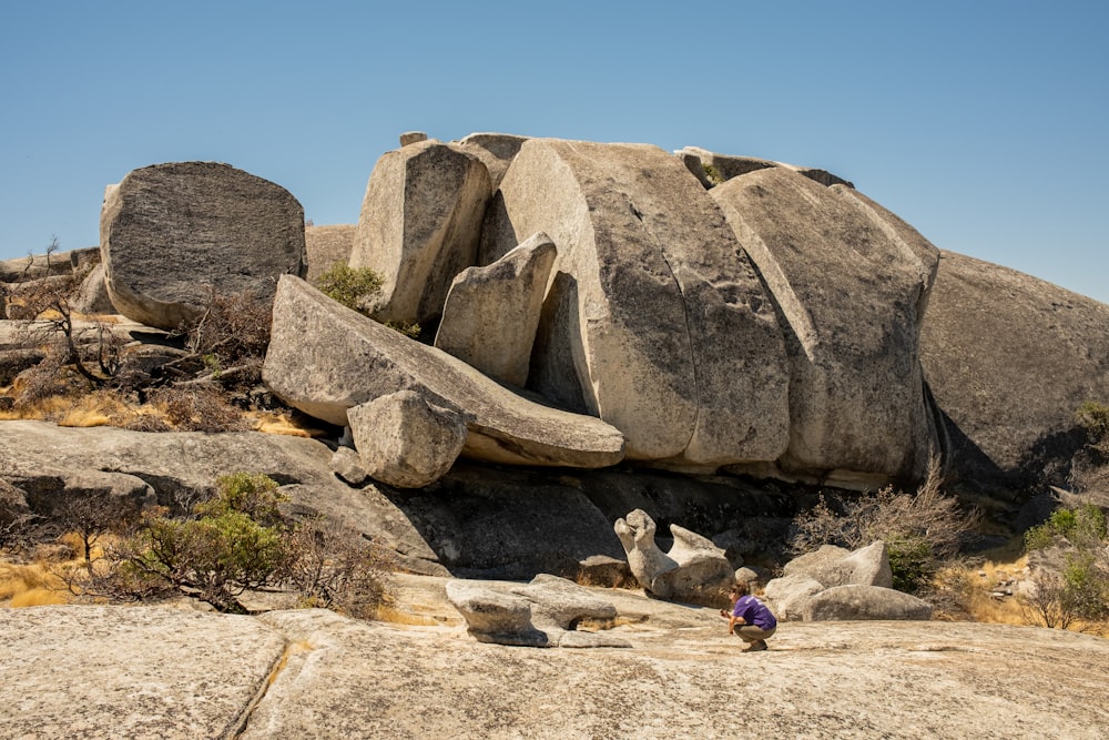 a child sitting in front of a large rock sculpture