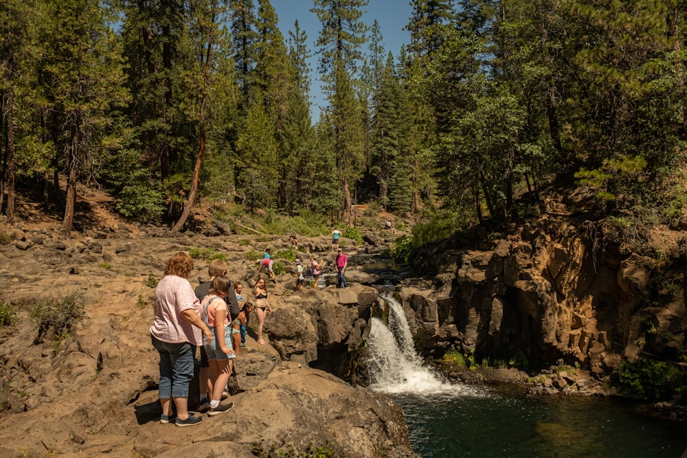 a group of people standing on a rocky cliff by a river