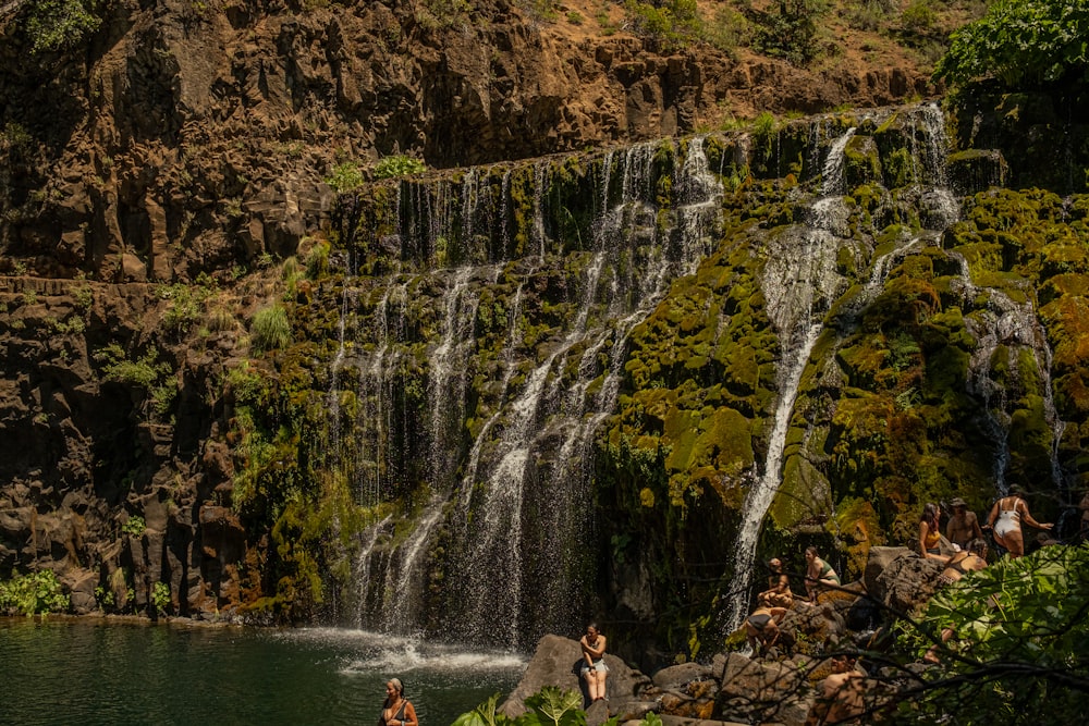 a waterfall with people standing on rocks