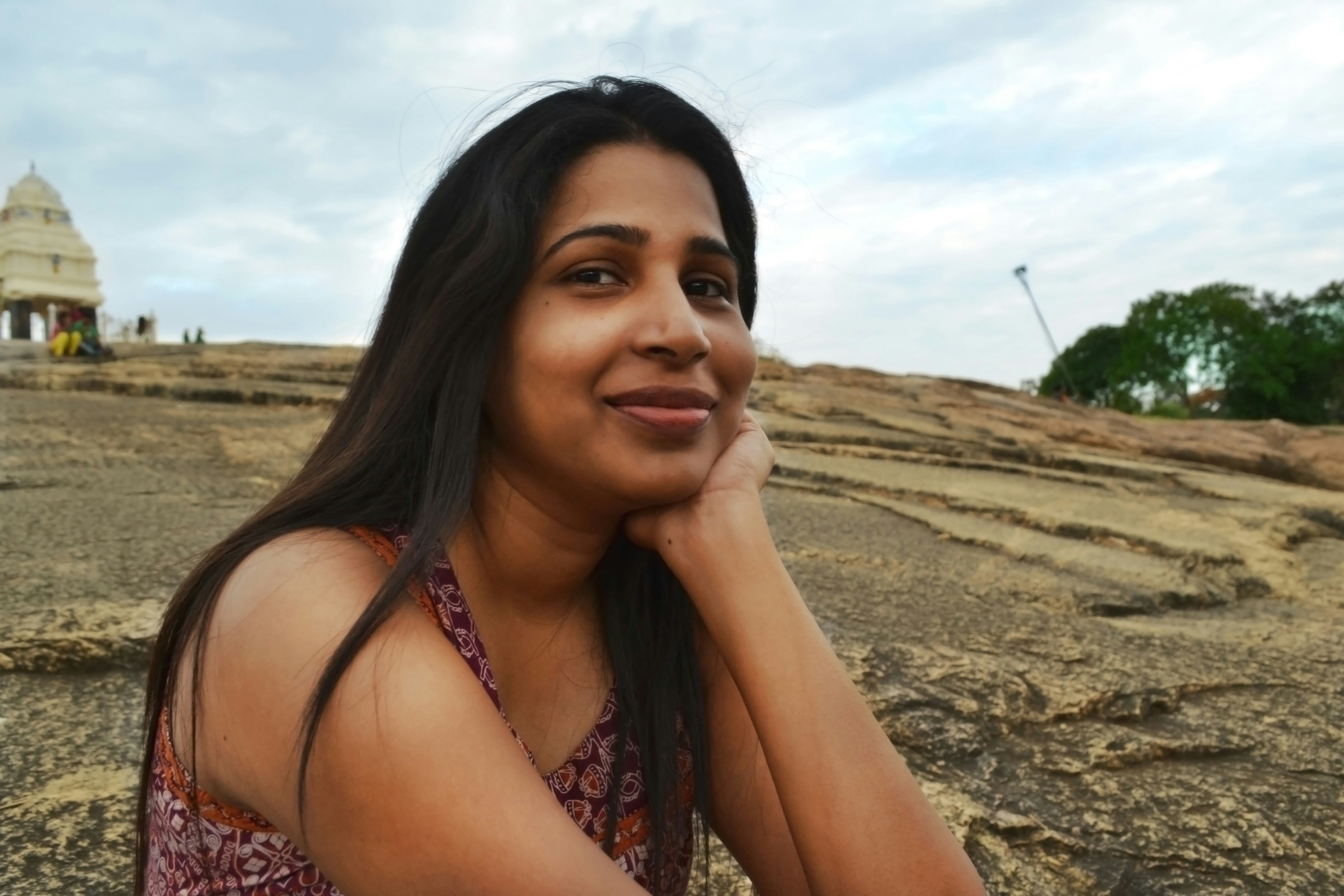 A woman smiles while resting her chin on her hand.