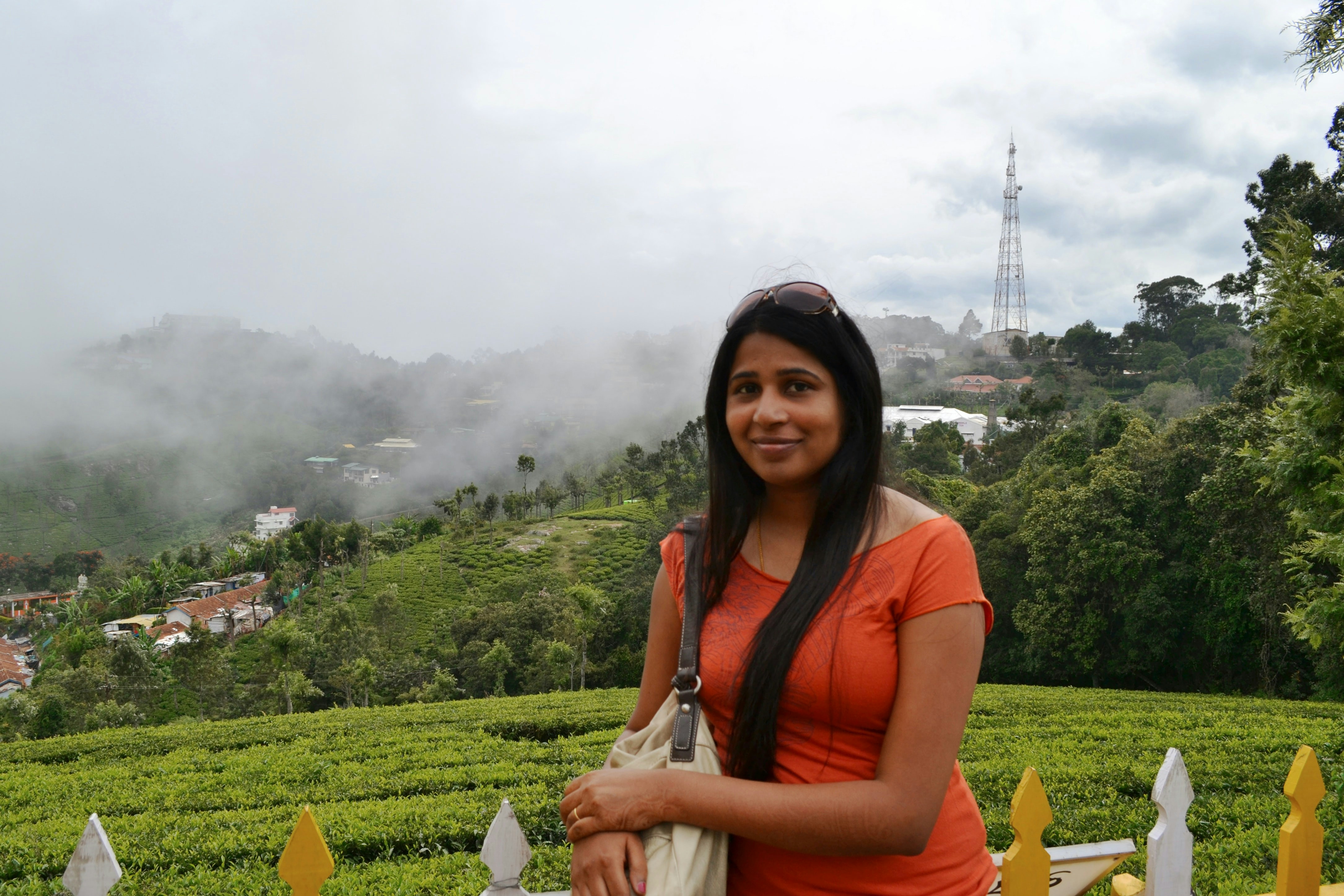 A woman poses in front of a misty mountain landscape.