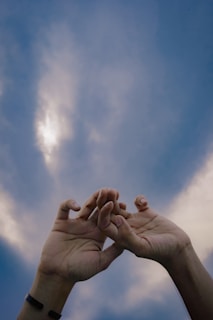 Hands raised in dua against a sunset sky, symbolizing hope and connection.