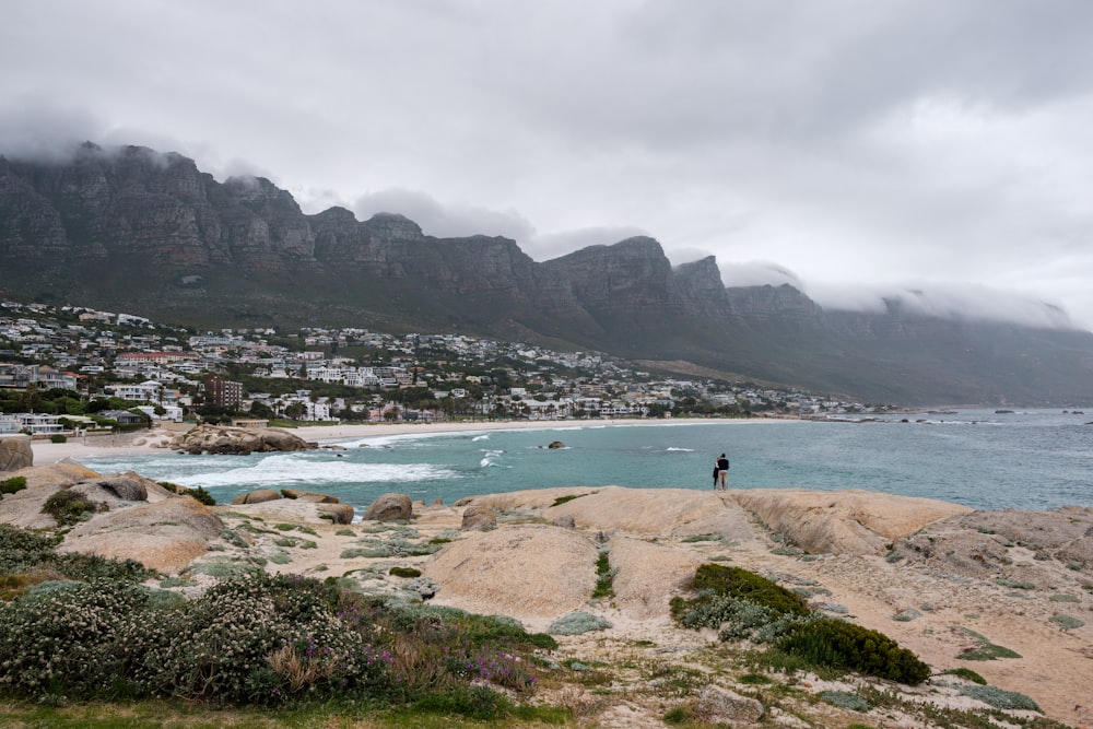 a beach with a body of water and a town in the distance