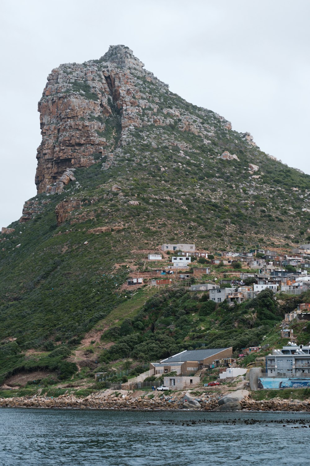 a large rock cliff with buildings below