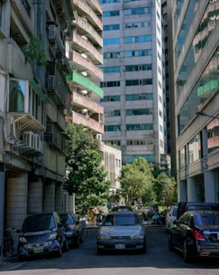 cars parked on the side of a street between buildings