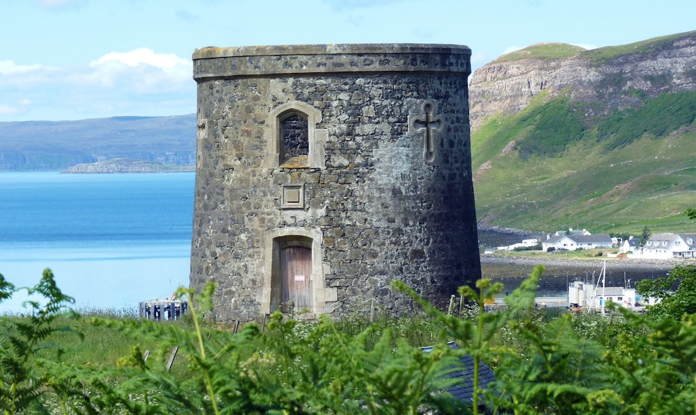 a stone building with a door and windows by a body of water