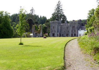 a large stone building with a grass lawn and trees