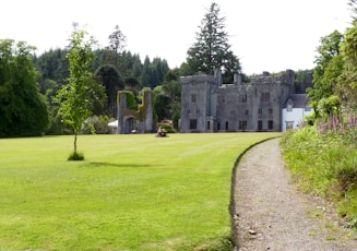 a large stone building with a grass lawn and trees