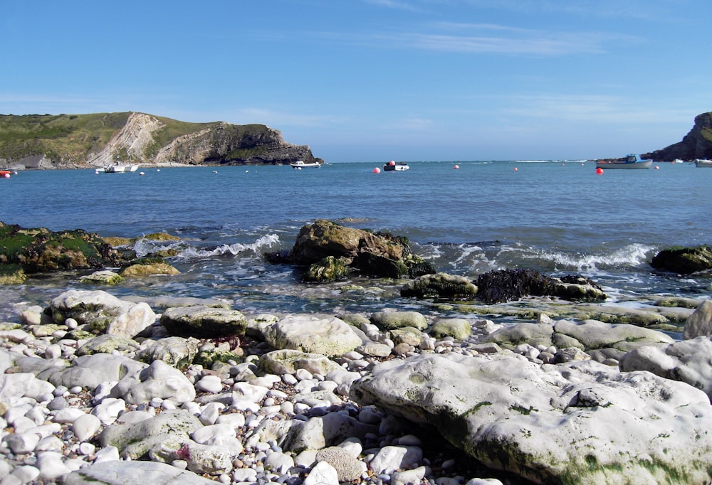 a rocky beach with boats in the water