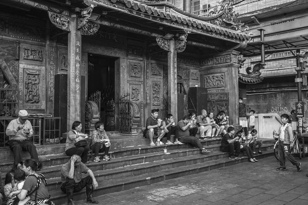 a group of people sitting on a bench in front of a building