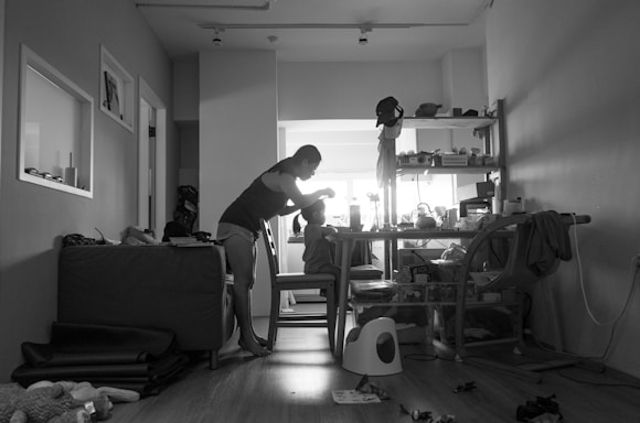 A candid photo of Andreea juggling work documents and playful moments with her two young boys at home.