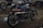 Several motorcycles, including a prominently featured custom Suzuki with a brown leather seat, are parked indoors. The environment appears to be a well-lit garage or workshop with a concrete floor.