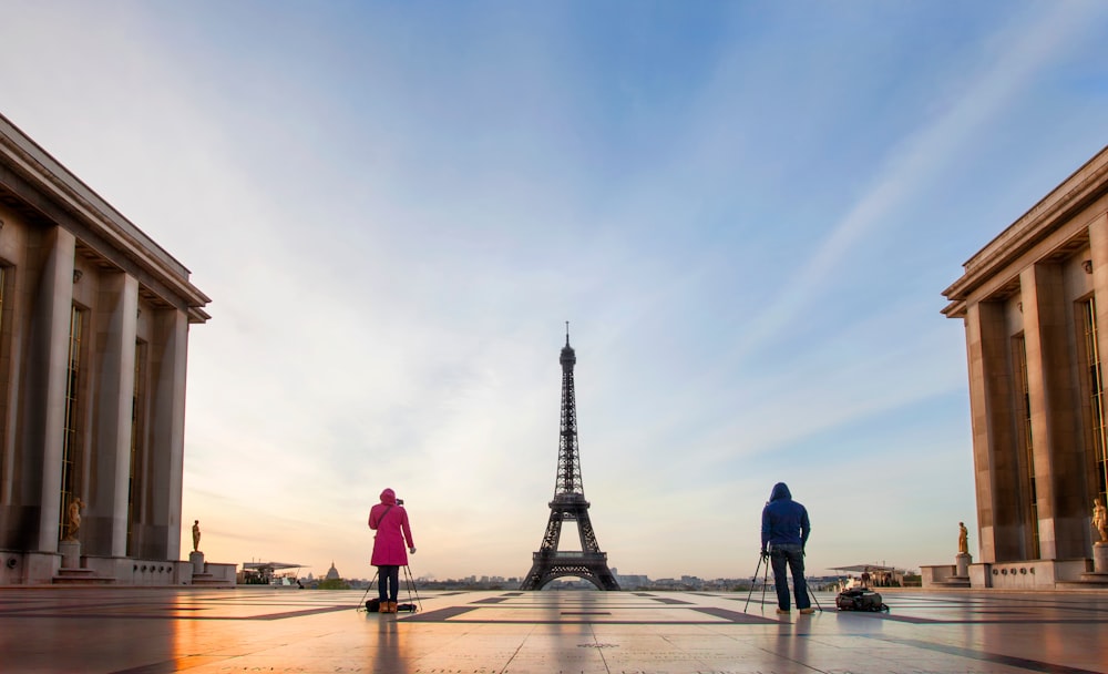 a man and a woman walking towards the eiffel tower