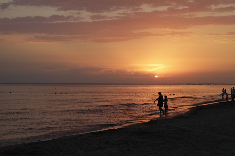 a group of people walk along the beach