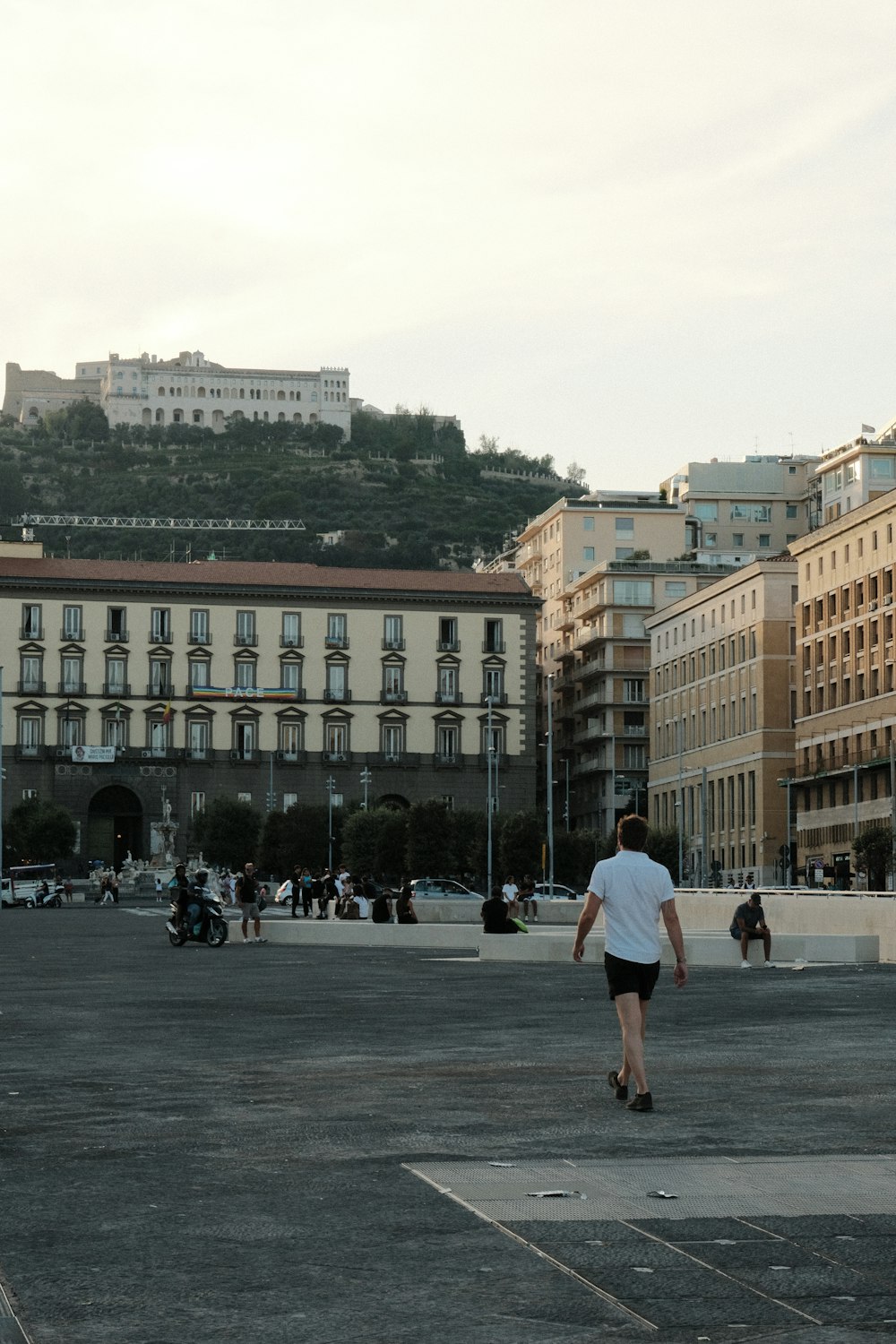 a man walking in a courtyard with buildings in the background