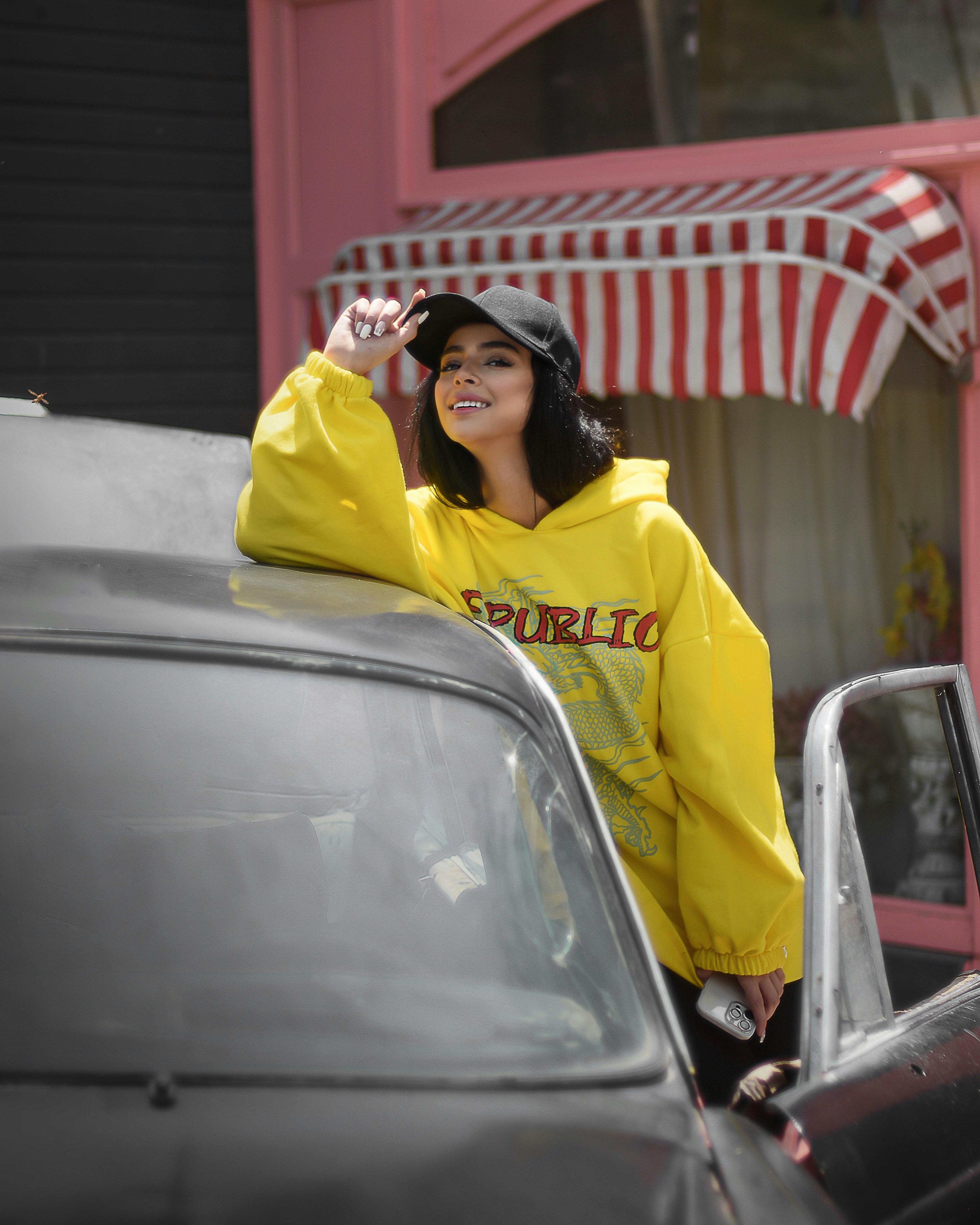 a person in a yellow jacket leaning on a car
