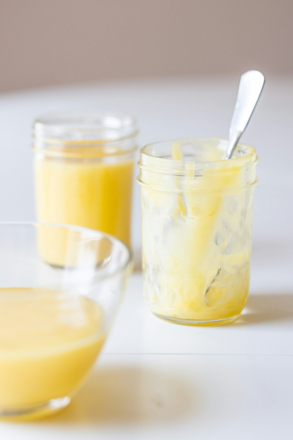 a group of glasses with yellow liquid and a spoon in it