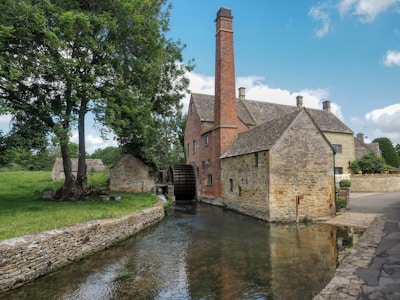 a stone building with a brick tower and a brick bridge over a river