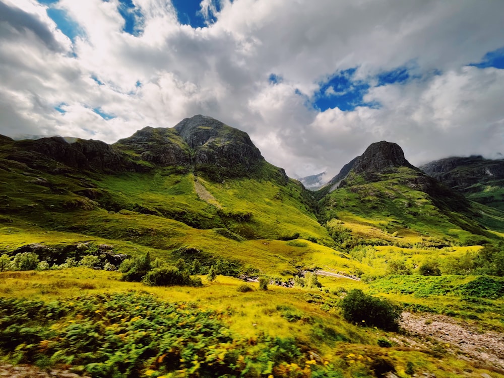 a grassy valley with mountains in the background