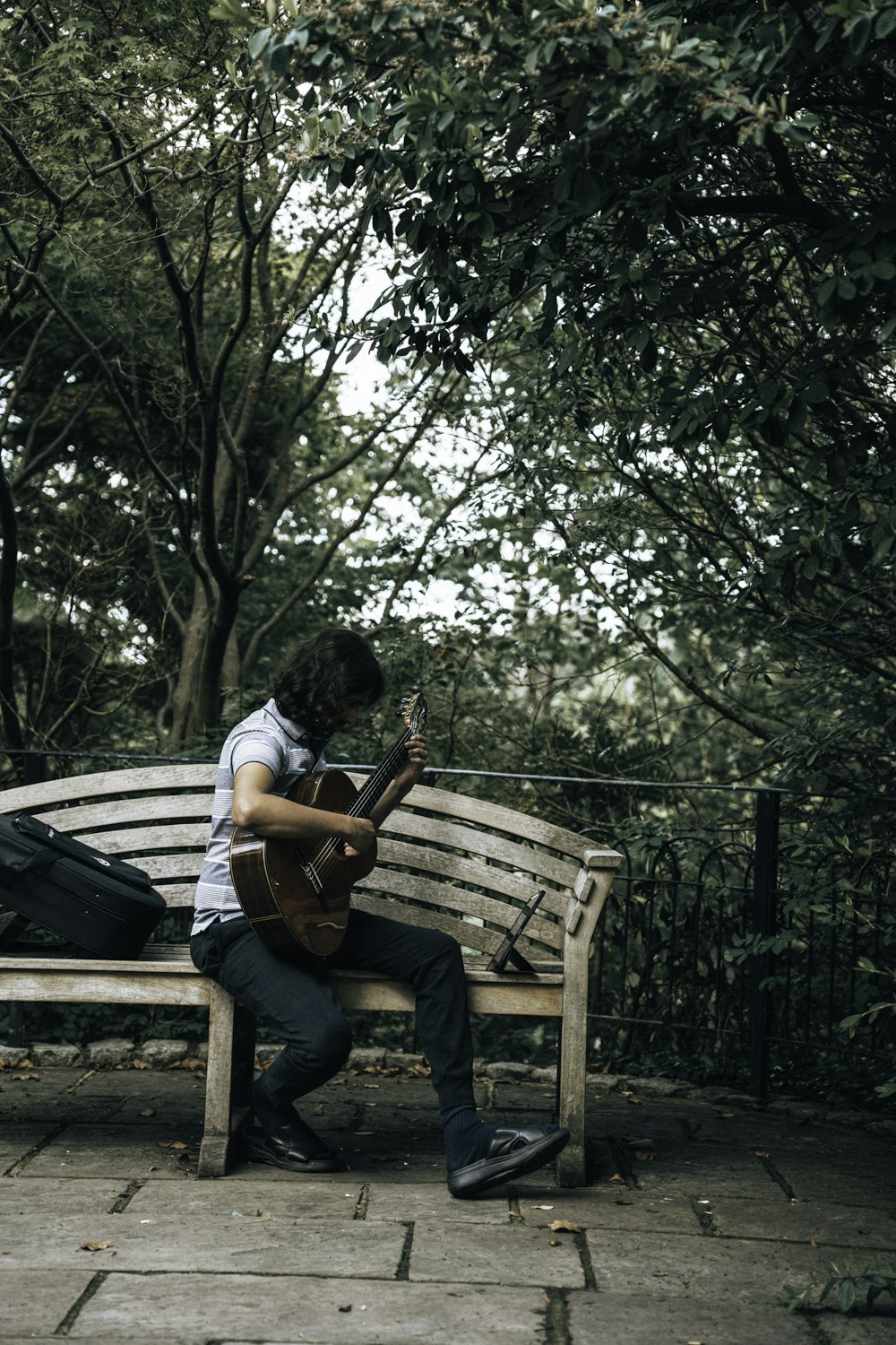a person playing a guitar on a bench