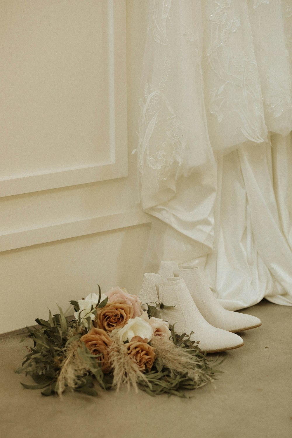 a pair of white shoes next to a bouquet of flowers
