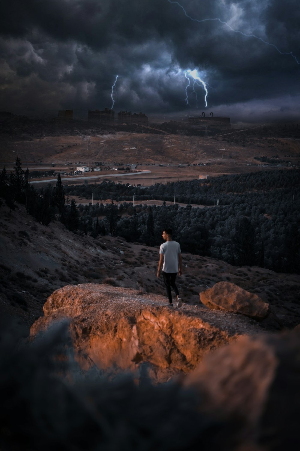 a person standing on a rock overlooking a valley with a lightning bolt