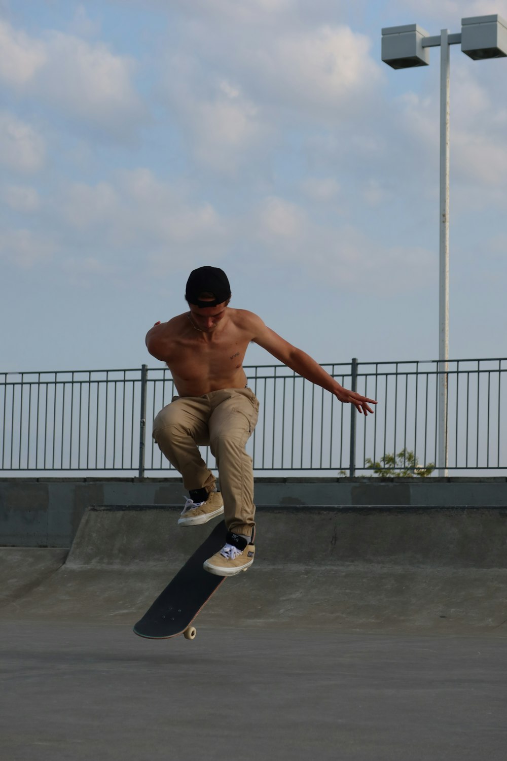 a shirtless man doing a trick on a skateboard