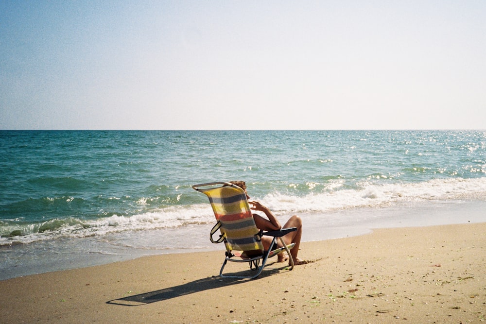 a person sitting in a chair on a beach