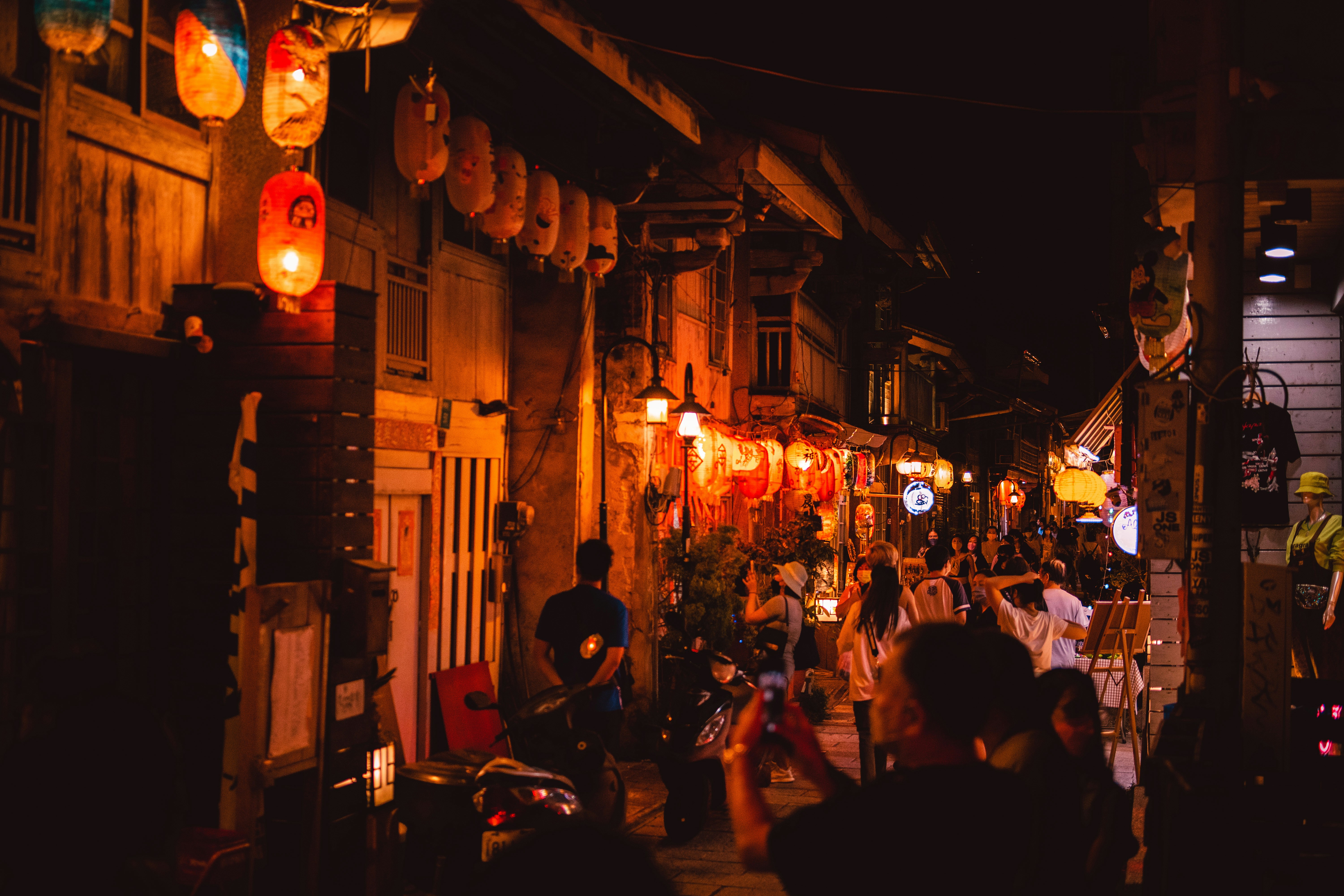 small tour group laughing and eating in a narrow, lantern-lit alleyway - osaka street food tour
