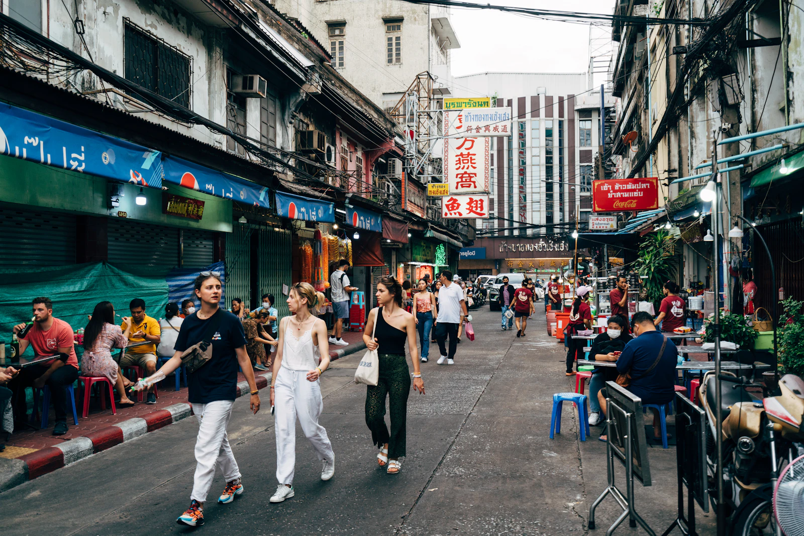 Bangkok street lined with shops and pedestrians.