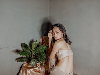 Model in a minimalist beige loungewear set sitting peacefully among wild sage greenery under gentle morning light.