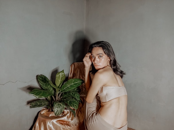 Model in a minimalist beige loungewear set sitting peacefully among wild sage greenery under gentle morning light.