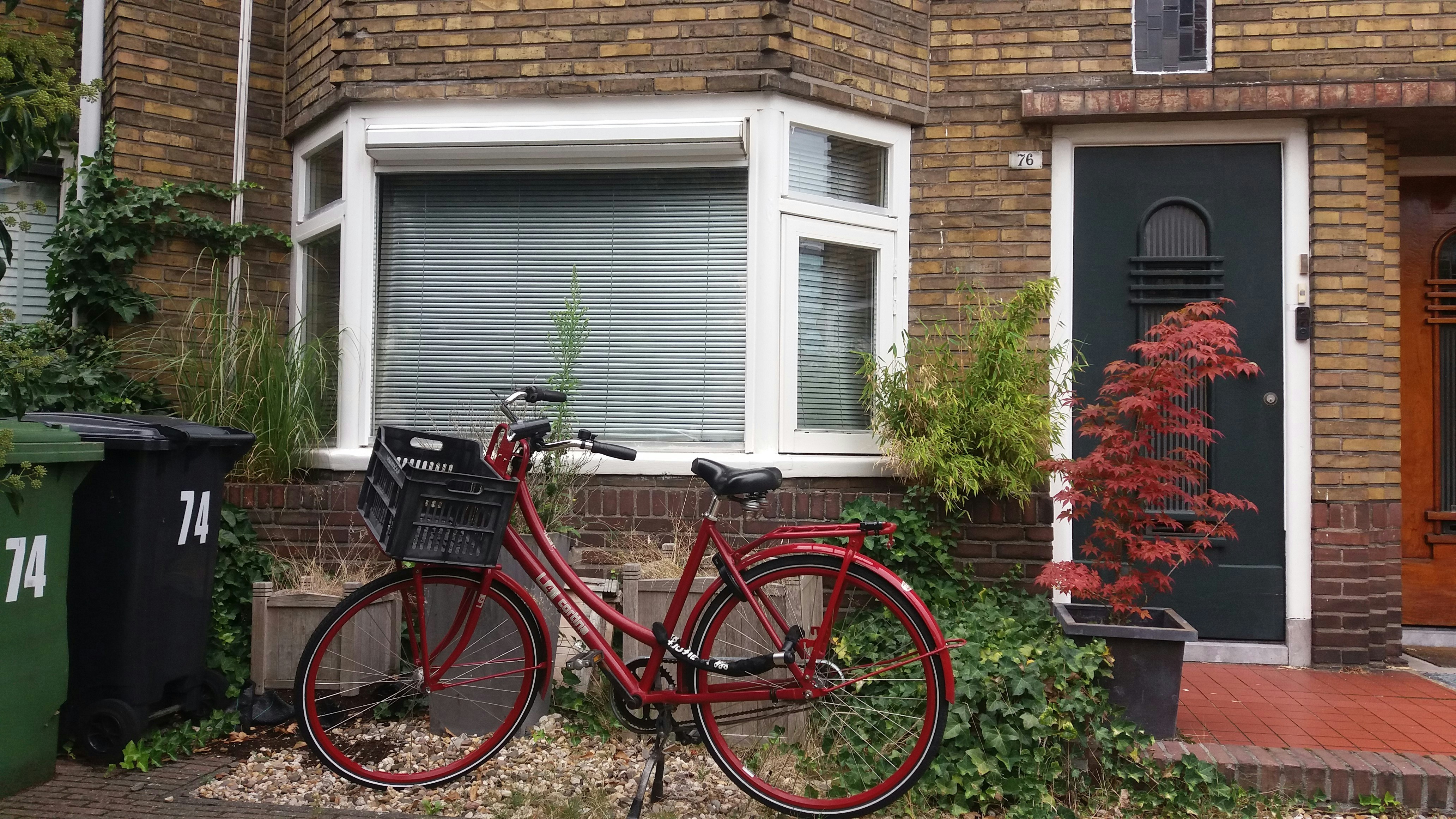 a red bicycle parked in front of a brick building