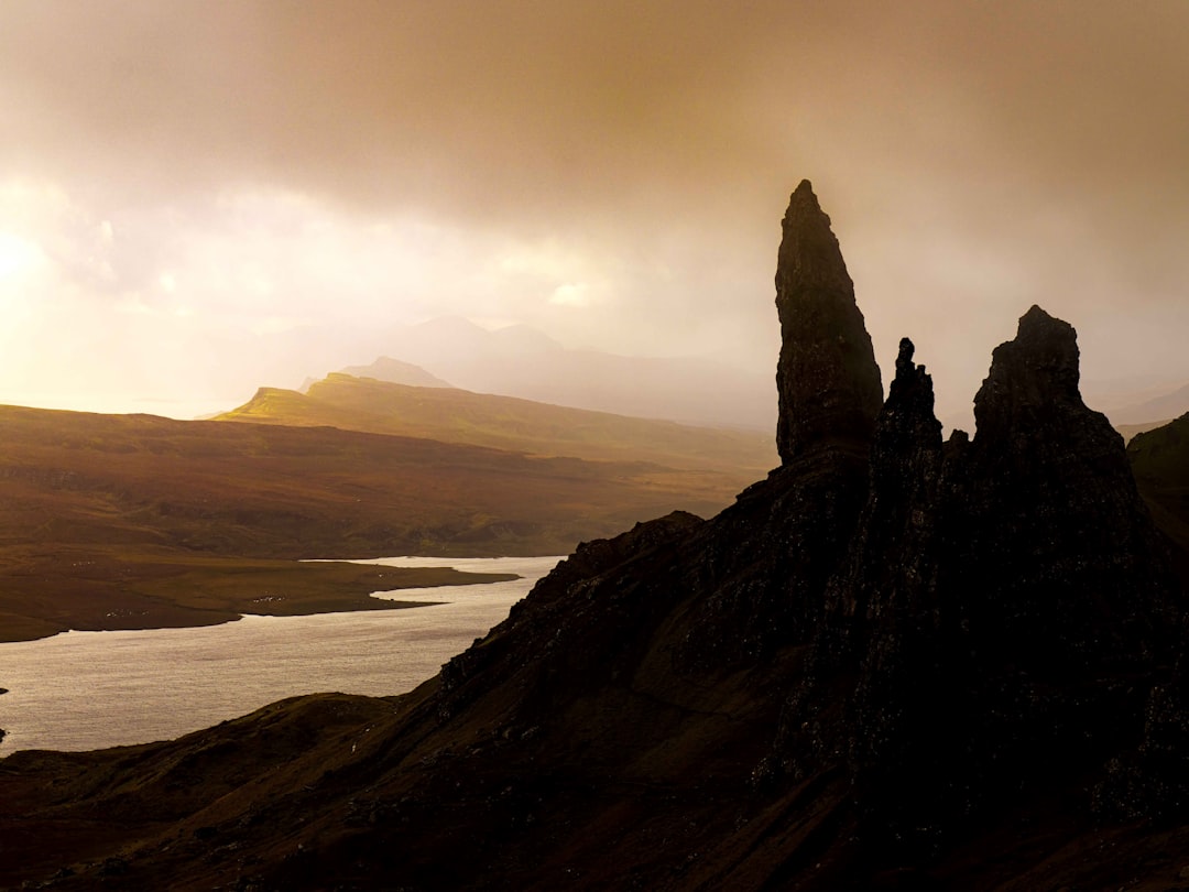 a rocky cliff with a body of water below, The old man of Storr on Skye in the morning light