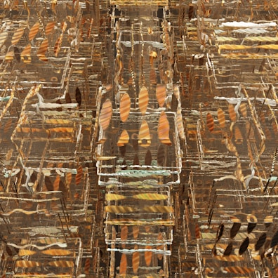 A complex, abstract pattern with layered, translucent geometrical shapes arranged in a grid-like formation. The shapes appear to be transparent, showcasing an array of earthy tones and metallic streaks giving an illusion of depth and texture.