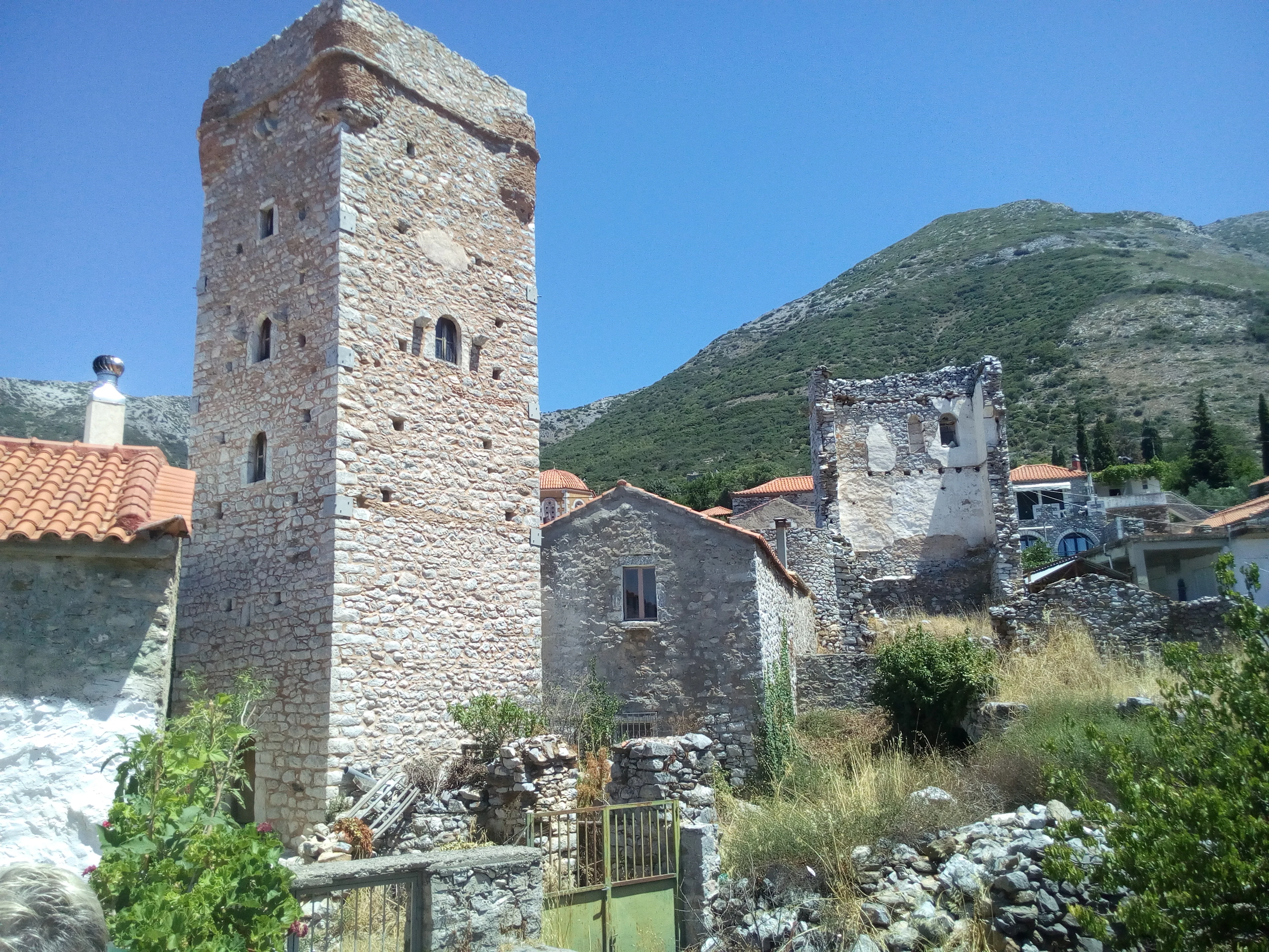 A stone tower house in a Mani village, with a hillside behind