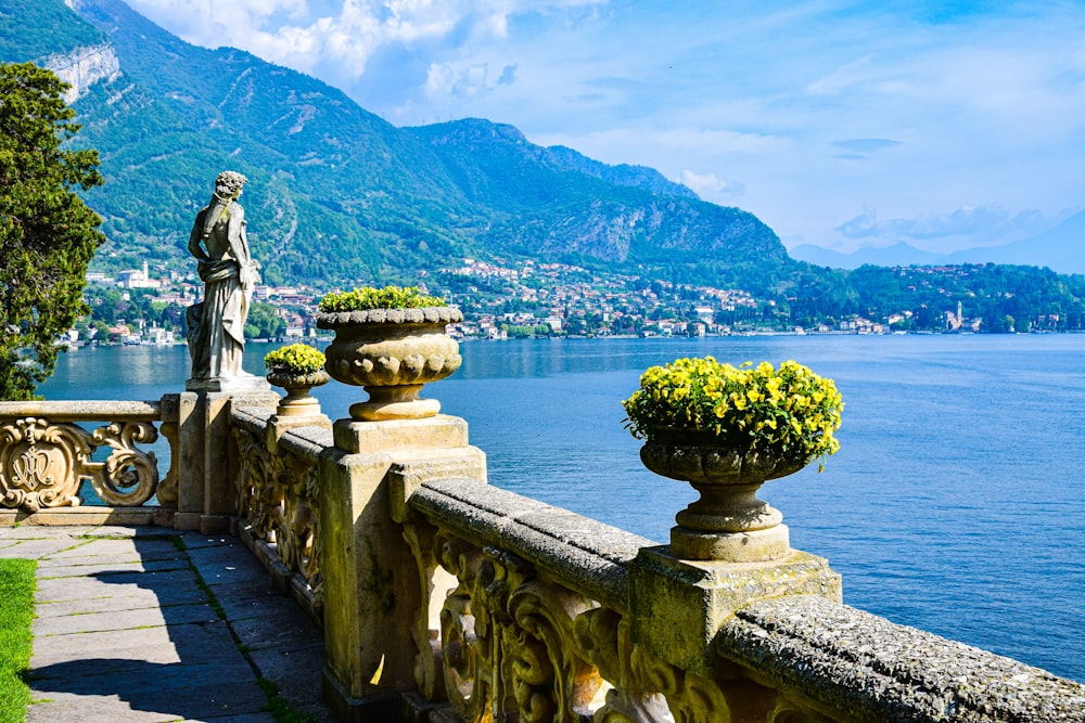 a statue on a stone wall overlooking a body of water