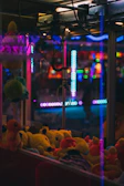 A claw machine filled with a variety of plush prizes, glowing under soft arcade lights.