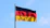 The flag of Germany waving on a metal pole against a blue sky